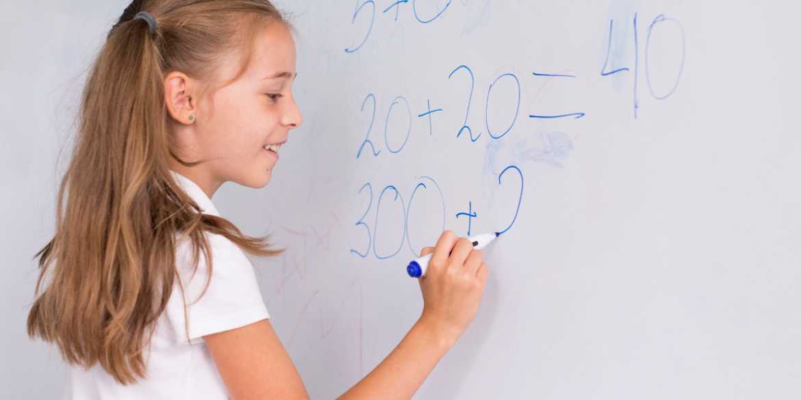 child in white school shirt using a whiteboard  marker pen 